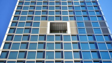 Ticari bina mavi tonda kapanıyor. Aşağıdan devasa bir gökdelen. Modern bina ve cam cephesinin mimari detayları. Güneşli bir günde iş geçmişi. 