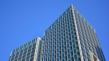 Ticari bina mavi tonda kapanıyor. Aşağıdan devasa bir gökdelen. Modern bina ve cam cephesinin mimari detayları. Güneşli bir günde iş geçmişi. 