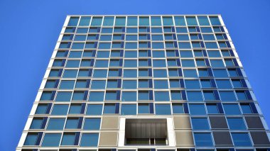 Ticari bina mavi tonda kapanıyor. Aşağıdan devasa bir gökdelen. Modern bina ve cam cephesinin mimari detayları. Güneşli bir günde iş geçmişi. 
