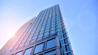 Ticari bina mavi tonda kapanıyor. Aşağıdan devasa bir gökdelen. Modern bina ve cam cephesinin mimari detayları. Güneşli bir günde iş geçmişi. 