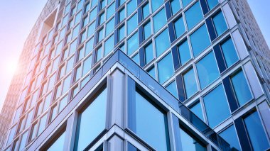 Ticari bina mavi tonda kapanıyor. Aşağıdan devasa bir gökdelen. Modern bina ve cam cephesinin mimari detayları. Güneşli bir günde iş geçmişi. 