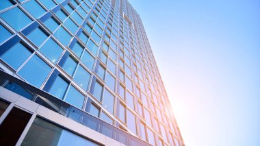 Ticari bina mavi tonda kapanıyor. Aşağıdan devasa bir gökdelen. Modern bina ve cam cephesinin mimari detayları. Güneşli bir günde iş geçmişi. 