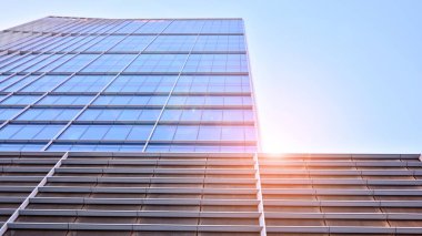 Ticari bina mavi tonda kapanıyor. Aşağıdan devasa bir gökdelen. Modern bina ve cam cephesinin mimari detayları. Güneşli bir günde iş geçmişi. 