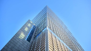 Ticari bina mavi tonda kapanıyor. Aşağıdan devasa bir gökdelen. Modern bina ve cam cephesinin mimari detayları. Güneşli bir günde iş geçmişi. 