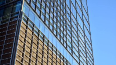 Ticari bina mavi tonda kapanıyor. Aşağıdan devasa bir gökdelen. Modern bina ve cam cephesinin mimari detayları. Güneşli bir günde iş geçmişi. 