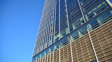 Ticari bina mavi tonda kapanıyor. Aşağıdan devasa bir gökdelen. Modern bina ve cam cephesinin mimari detayları. Güneşli bir günde iş geçmişi. 