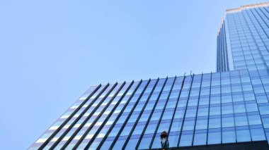 Ticari bina mavi tonda kapanıyor. Aşağıdan devasa bir gökdelen. Modern bina ve cam cephesinin mimari detayları. Güneşli bir günde iş geçmişi. 