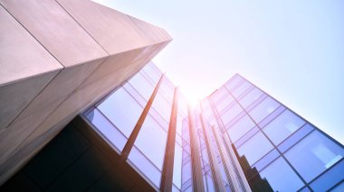 Ticari bina mavi tonda kapanıyor. Aşağıdan devasa bir gökdelen. Modern bina ve cam cephesinin mimari detayları. Güneşli bir günde iş geçmişi. 