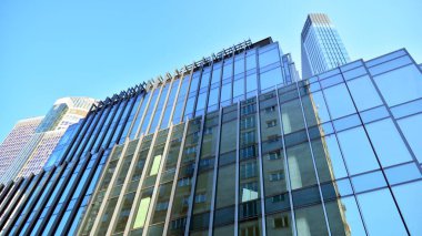 Ticari bina mavi tonda kapanıyor. Aşağıdan devasa bir gökdelen. Modern bina ve cam cephesinin mimari detayları. Güneşli bir günde iş geçmişi. 