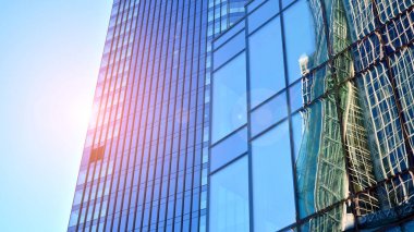 Ticari bina mavi tonda kapanıyor. Aşağıdan devasa bir gökdelen. Modern bina ve cam cephesinin mimari detayları. Güneşli bir günde iş geçmişi. 