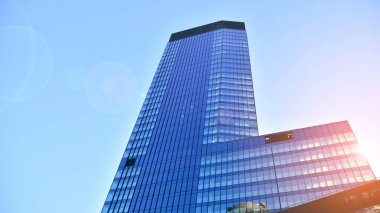Ticari bina mavi tonda kapanıyor. Aşağıdan devasa bir gökdelen. Modern bina ve cam cephesinin mimari detayları. Güneşli bir günde iş geçmişi. 