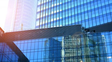 Ticari bina mavi tonda kapanıyor. Aşağıdan devasa bir gökdelen. Modern bina ve cam cephesinin mimari detayları. Güneşli bir günde iş geçmişi. 