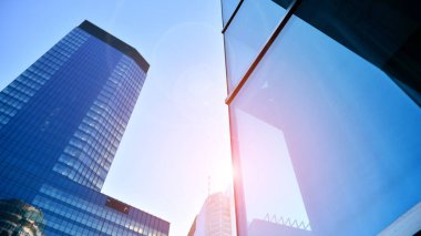 Ticari bina mavi tonda kapanıyor. Aşağıdan devasa bir gökdelen. Modern bina ve cam cephesinin mimari detayları. Güneşli bir günde iş geçmişi. 