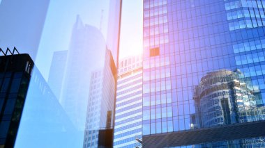 Ticari bina mavi tonda kapanıyor. Aşağıdan devasa bir gökdelen. Modern bina ve cam cephesinin mimari detayları. Güneşli bir günde iş geçmişi. 