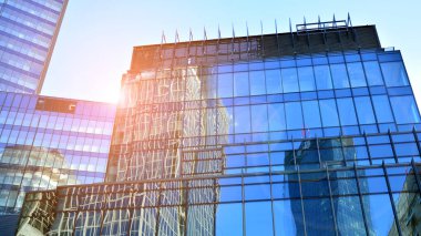 Ticari bina mavi tonda kapanıyor. Aşağıdan devasa bir gökdelen. Modern bina ve cam cephesinin mimari detayları. Güneşli bir günde iş geçmişi. 