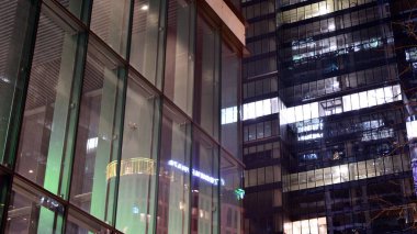 Geceleri ofis binası, cam ve ışıklarla dolu bir bina. Aydınlatılmış modern gökdelen ile arka plan.