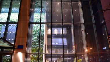 Geceleri ofis binası, cam ve ışıklarla dolu bir bina. Aydınlatılmış modern gökdelen ile arka plan.