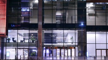 Geceleri ofis binası, cam ve ışıklarla dolu bir bina. Aydınlatılmış modern gökdelen ile arka plan.