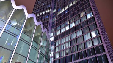 Office building at night, building facade with glass and lights. View with illuminated modern skyscraper.