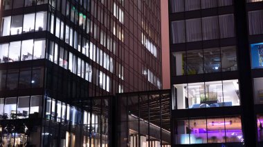 Geceleri ofis binası, cam ve ışıklarla bina cephesi. Aydınlatılmış modern gökdelen ile görüntüle.