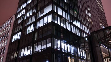 Office building at night, building facade with glass and lights. View with illuminated modern skyscraper.