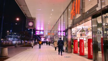 Warsaw, Poland. 11 January 2022. Centrum city evening and people walking on sidewalk by shop windows after work.