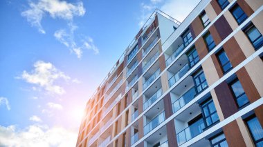 Mavi gökyüzüne karşı birçok penceresi olan ön bina.