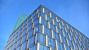 Güneşli bir günde gökyüzünün yansımasıyla modern cam şirket mimarisi