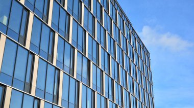 Güneşli bir günde gökyüzünün yansımasıyla modern cam şirket mimarisi