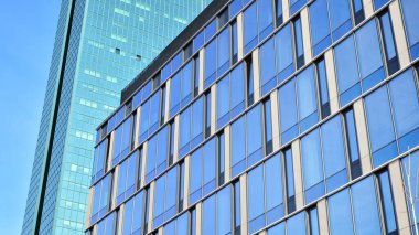 Güneşli bir günde gökyüzünün yansımasıyla modern cam şirket mimarisi