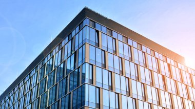 Güneşli bir günde gökyüzünün yansımasıyla modern cam şirket mimarisi