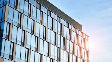 Güneşli bir günde gökyüzünün yansımasıyla modern cam şirket mimarisi