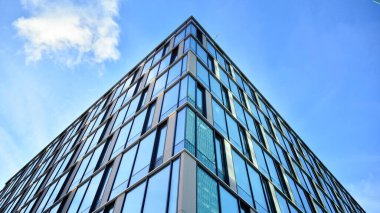 Güneşli bir günde gökyüzünün yansımasıyla modern cam şirket mimarisi