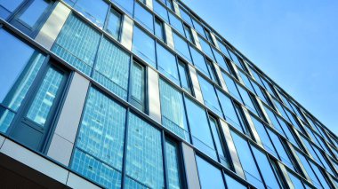 Güneşli bir günde gökyüzünün yansımasıyla modern cam şirket mimarisi