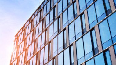 Güneşli bir günde gökyüzünün yansımasıyla modern cam şirket mimarisi