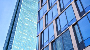 Güneşli bir günde gökyüzünün yansımasıyla modern cam şirket mimarisi