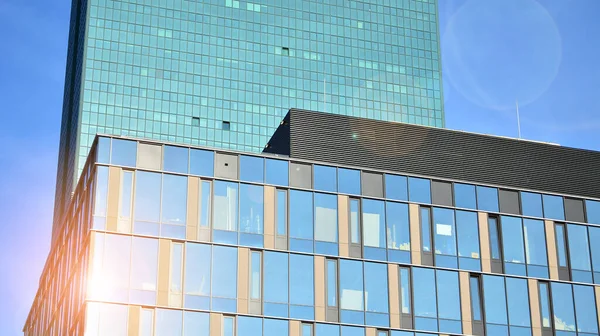 Güneşli bir günde gökyüzünün yansımasıyla modern cam şirket mimarisi