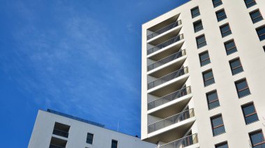 Modern lüks konut dairesi. Güneşli bir günde modern apartman binası. Mavi gökyüzü olan beyaz bir apartman. Modern bir apartmanın cephesi.