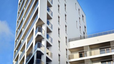 Modern lüks konut dairesi. Güneşli bir günde modern apartman binası. Mavi gökyüzü olan beyaz bir apartman. Modern bir apartmanın cephesi.