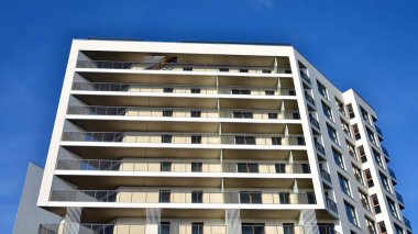 Modern lüks konut dairesi. Güneşli bir günde modern apartman binası. Mavi gökyüzü olan beyaz bir apartman. Modern bir apartmanın cephesi.