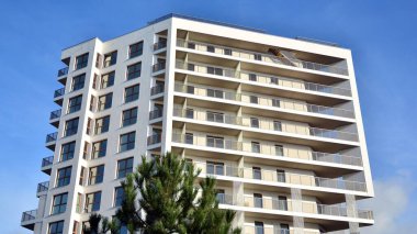 Modern lüks konut dairesi. Güneşli bir günde modern apartman binası. Mavi gökyüzü olan beyaz bir apartman. Modern bir apartmanın cephesi.