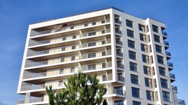 Modern lüks konut dairesi. Güneşli bir günde modern apartman binası. Mavi gökyüzü olan beyaz bir apartman. Modern bir apartmanın cephesi.