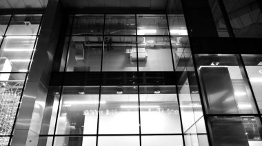 İnanılmaz bir gece manzarası. Geceleri ofis binası, cam ve ışıklarla bina cephesi. Aydınlatılmış modern gökdelen manzarası. Akşamları gökdelenlerin parlayan manzaralı pencereleri. Siyah ve beyaz.