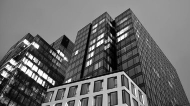 İnanılmaz bir gece manzarası. Geceleri ofis binası, cam ve ışıklarla bina cephesi. Aydınlatılmış modern gökdelen manzarası. Akşamları gökdelenlerin parlayan manzaralı pencereleri. Siyah ve beyaz.