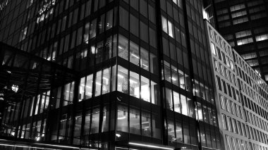 İnanılmaz bir gece manzarası. Geceleri ofis binası, cam ve ışıklarla bina cephesi. Aydınlatılmış modern gökdelen manzarası. Akşamları gökdelenlerin parlayan manzaralı pencereleri. Siyah ve beyaz.