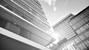 Yeni modern ofis binasının yanında camdan yüzlü modern bir apartman manzarası. Siyah ve beyaz.