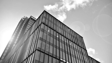 Şehir merkezindeki soyut ve karmaşık gökdelen yapısının arka planında gökyüzü ve güneş var. Siyah ve beyaz.