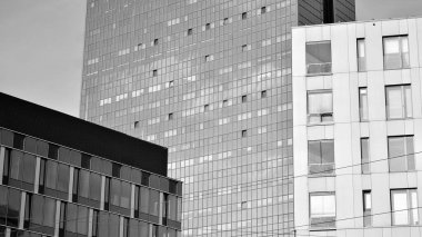 Yeni modern ofis binasının yanında camdan yüzlü modern bir apartman manzarası. Siyah ve beyaz.