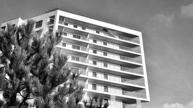 Modern lüks konut dairesi. Güneşli bir günde modern apartman binası. Mavi gökyüzü olan beyaz bir apartman. Modern bir apartmanın ön cephesi. Siyah ve beyaz.