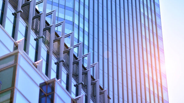 Fragments of building in business district of modern city. High-rise office building in downtown. Modern architecture of typical concrete, glass and steel.